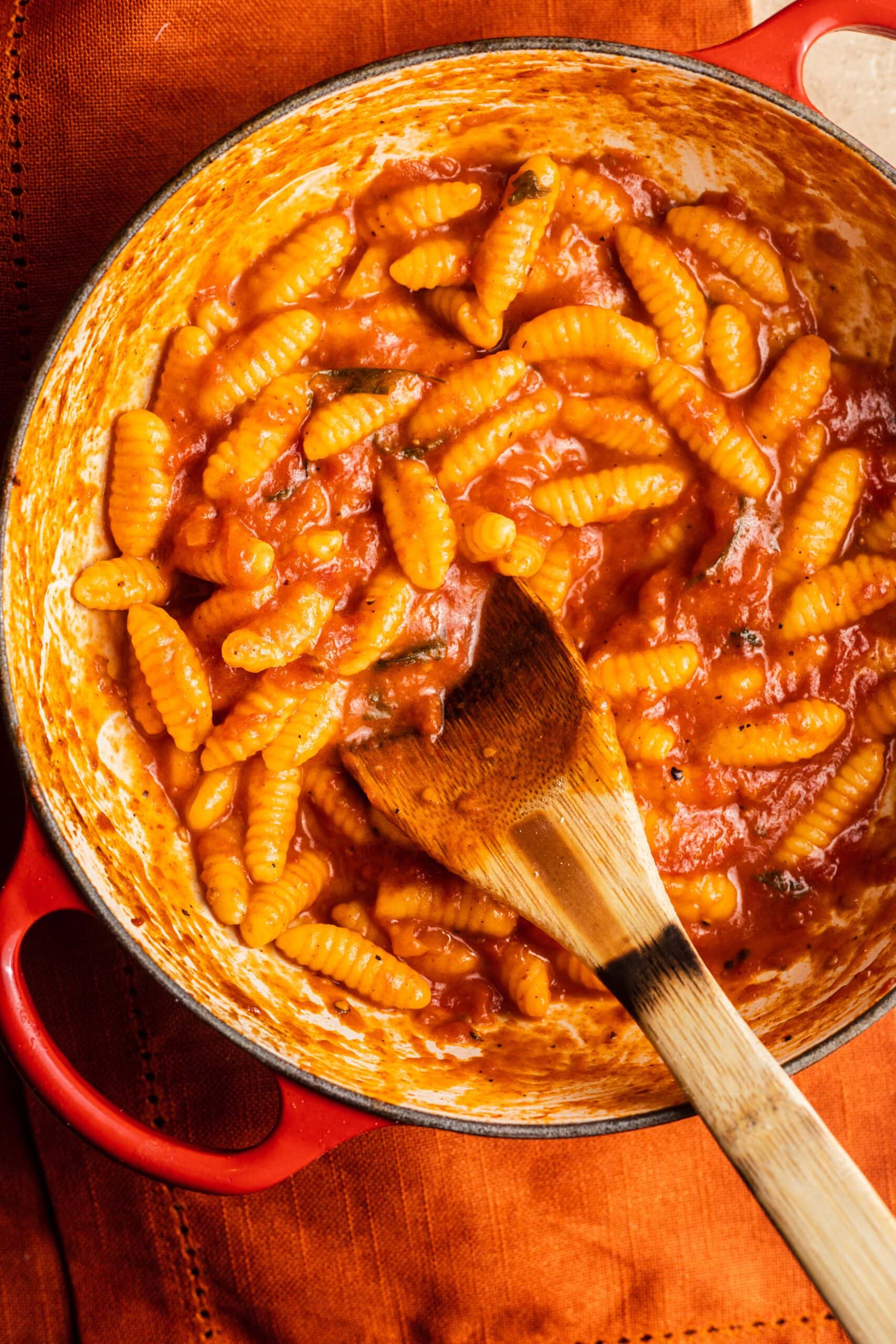 A dutch oven with malloreddus pasta tossed in a tomato butter sauce.