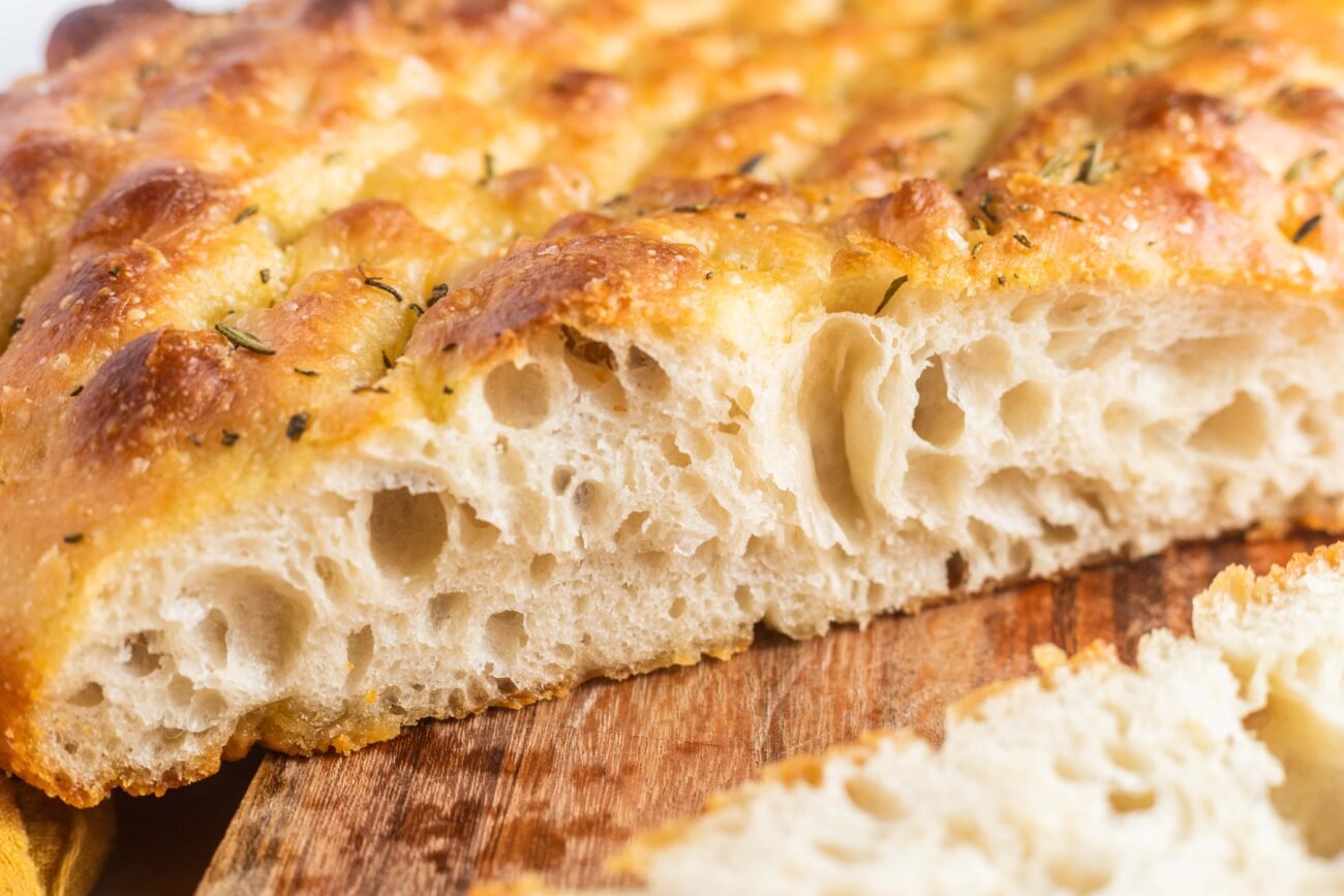A loaf of focaccia cut in half with a slice on the side.