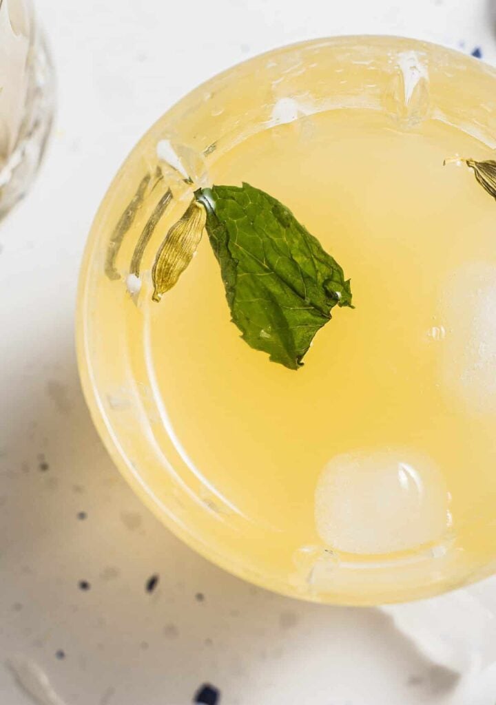 A glass of limbu sarbat with mint and cardamom