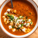 Bowl of chickpea pepper soup with feta and herbs.