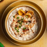 Bowl of dip topped with a chili oil, scallions, and a few tortilla chips.