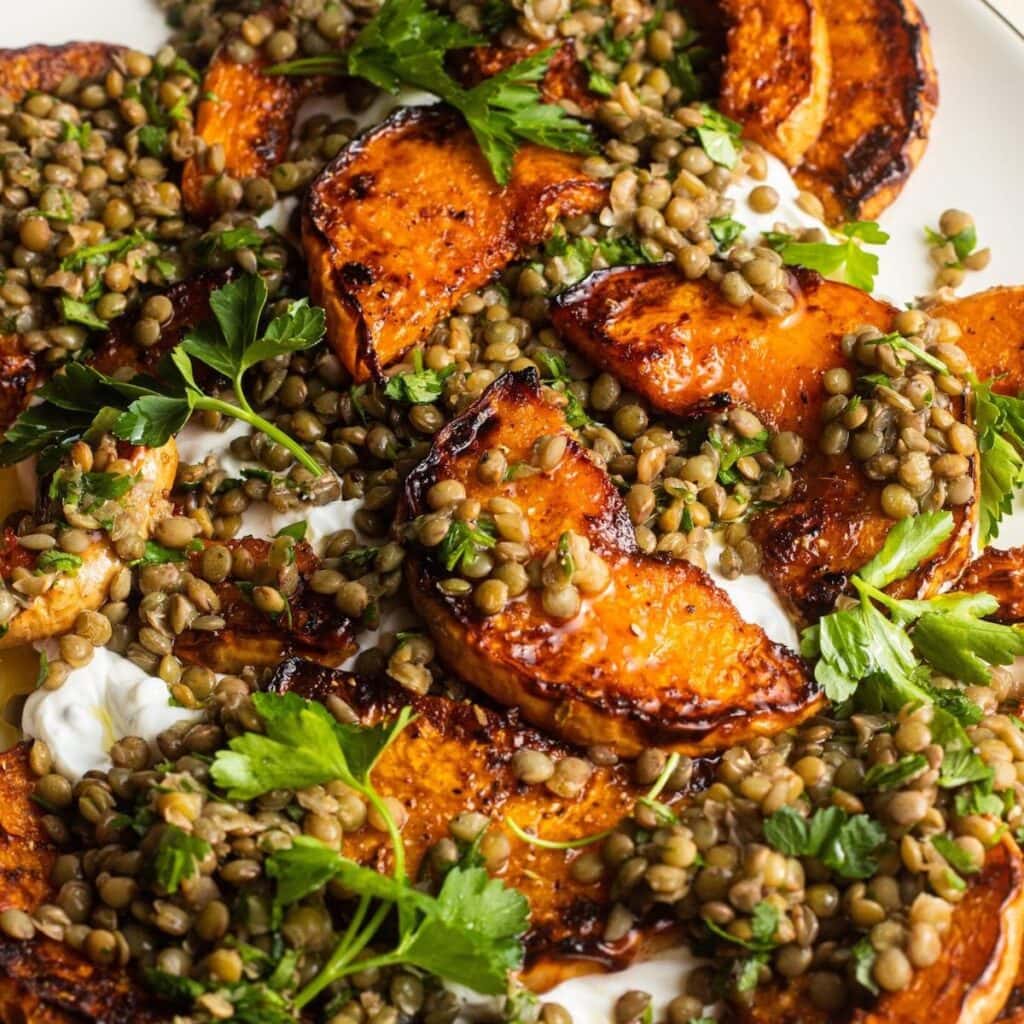 Roasted squash with lentils, herbs, and labneh on a serving plate.