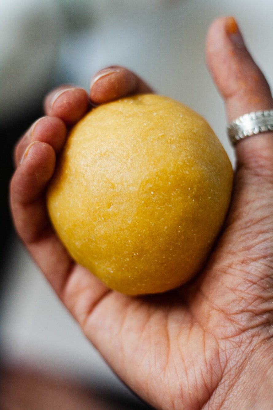 Hand holding a ball of pasta dough.