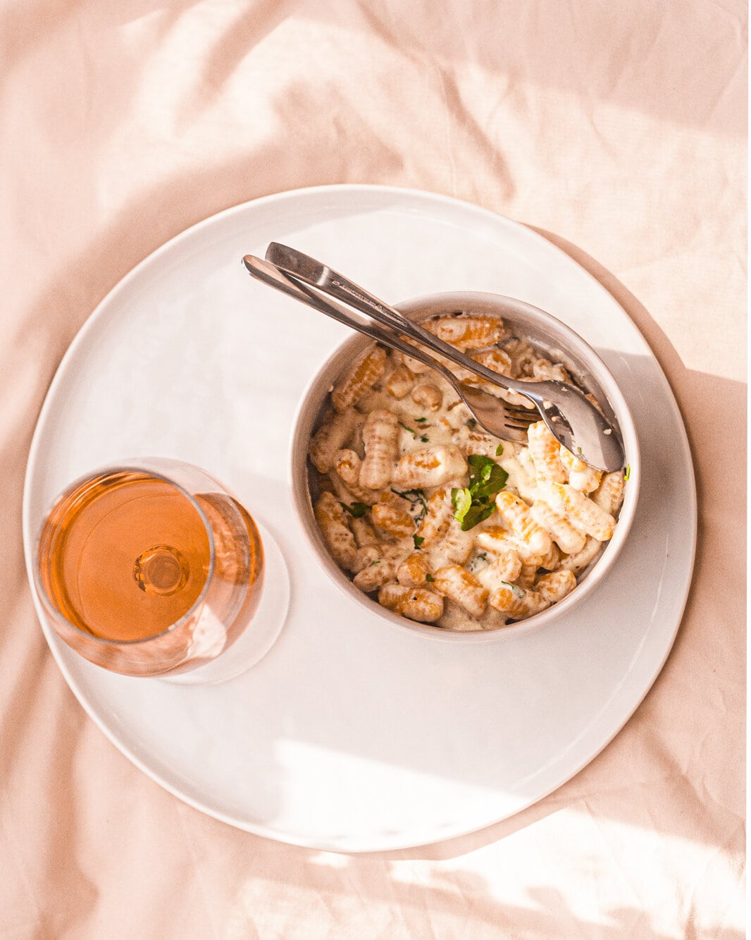 Bowl of cavatelli with a wine glass on a plate.
