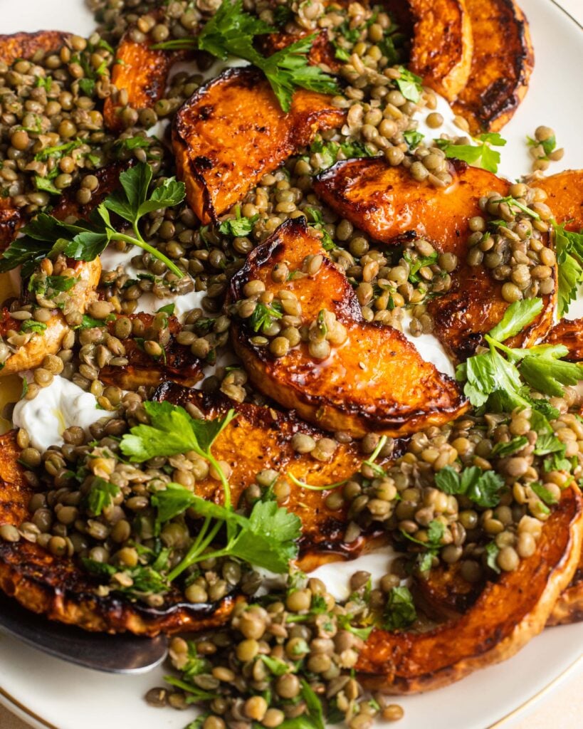 Roasted squash with lentils and yogurt on a serving plate.