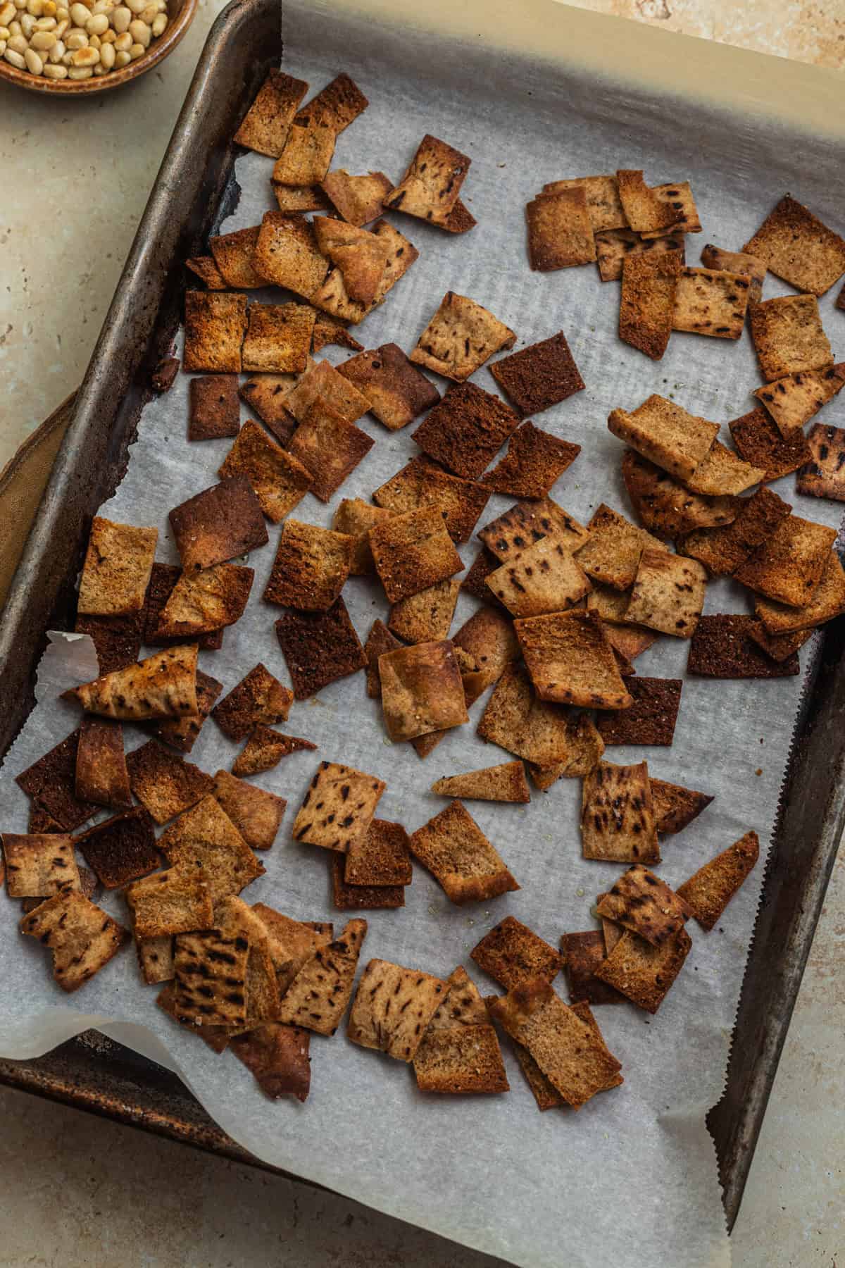 Cut-up pieces of pita baked on a parchment-lined baking sheet.