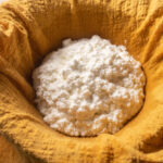 Creamy ricotta draining in a yellow kitchen towel.