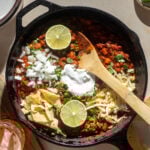 Small batch chili in a cast-iron skillet with tortilla chips, lime, and sour cream.