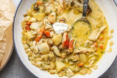 A bowl of crab stew with potatoes, fish, and other vegetables, topped with a dollop of yogurt.
