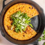 Socca (chickpea pancake) in a cast-iron skillet with herbs on top.