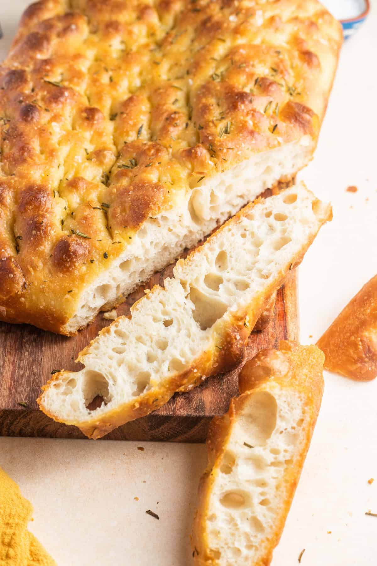 A large slab of focaccia with the end pieces sliced off sitting on a cutting board.