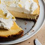 Lemon gingersnap cheesecake topped with whipped cream in a baking pan.