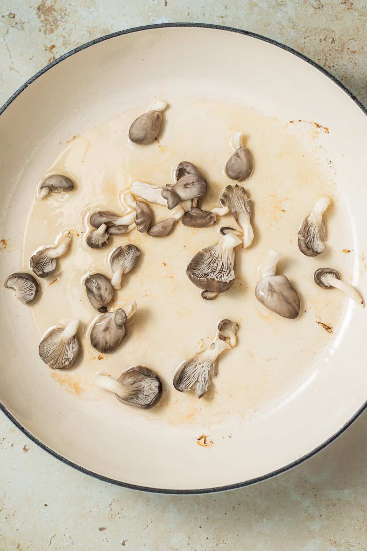 A large pan with raw oyster mushrooms pieces ready to be cooked.