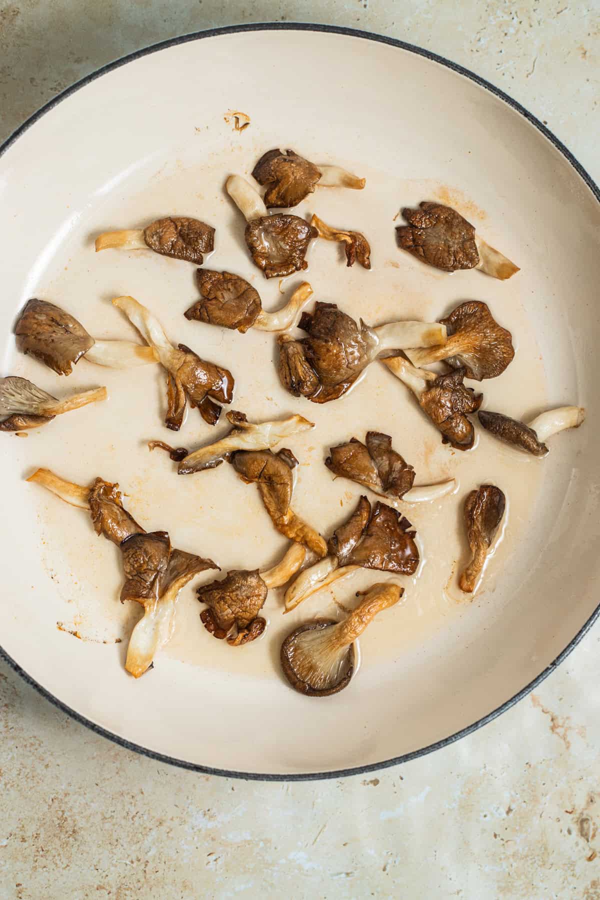 A large pan with oyster mushrooms crisped up and golden brown in oil.
