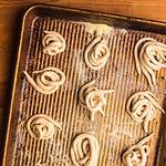Nests of pici pasta on a semolina dusted baking sheet.