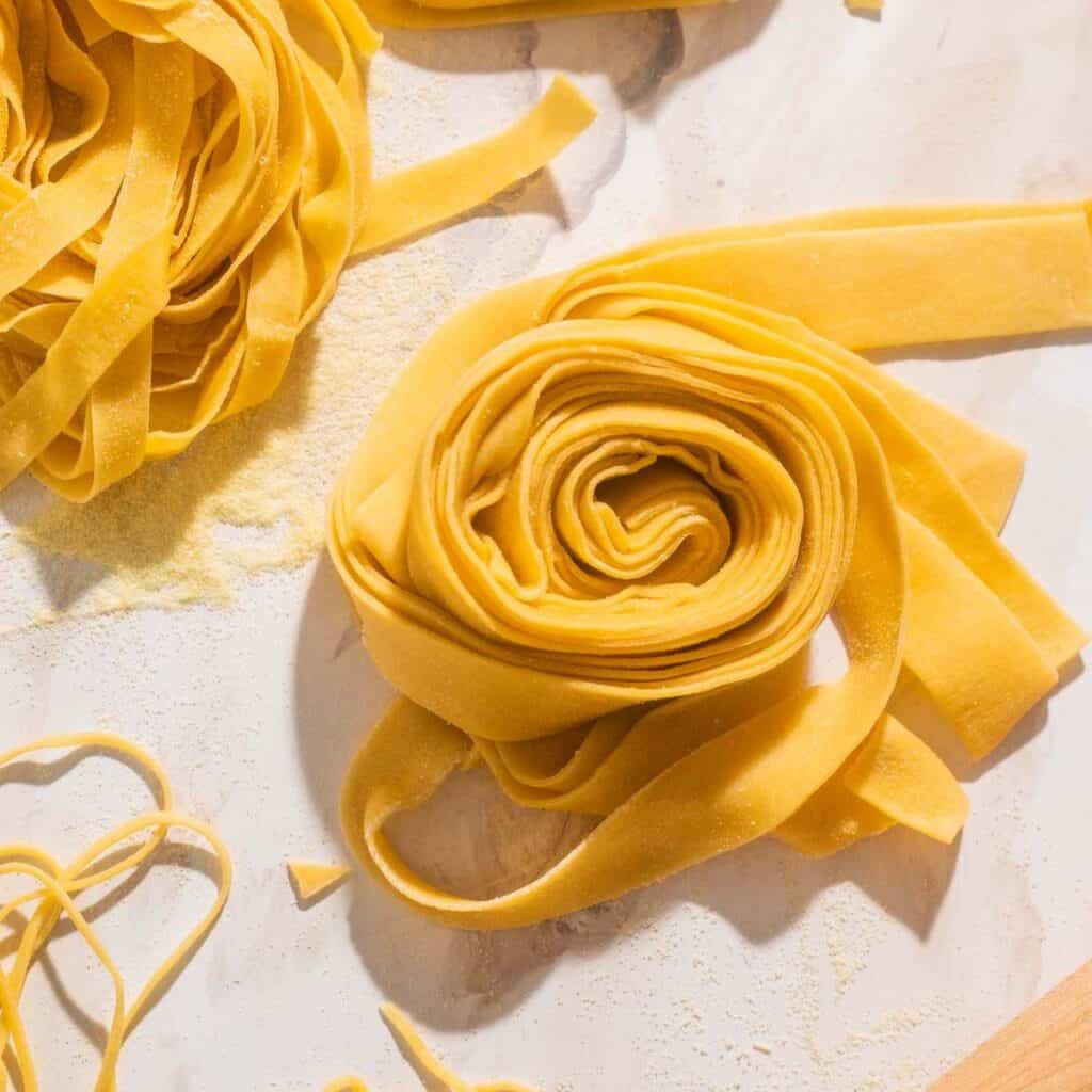 Nests of egg pasta in various sizes dusted with semolina flour.