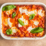 Casserole dish with baked gnocchi in a tomato sauce and basil on top