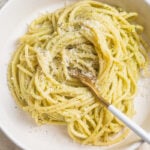 White bowl with pesto pasta twirled around a fork.