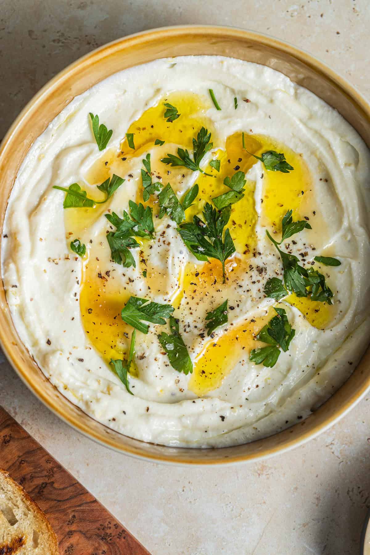 A bowl of whipped ricotta dip topped with oil and herbs.