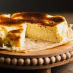 Mini basque cheesecake with a slice cut out on a cake stand.