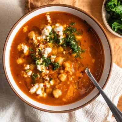 Bowl of chickpea soup topped with herbs and feta cheese.