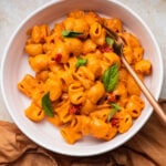 Bowl of spicy vodka pasta with herbs and calabrian chilies on top.