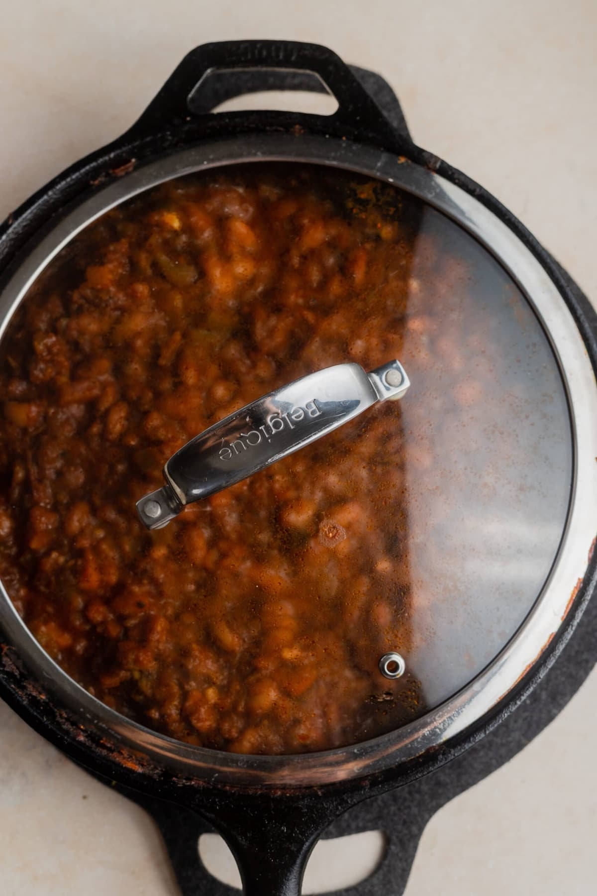 A lidded skillet of vegetarian chili set to simmer.