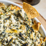 Chip dipped in artichoke dip casserole.