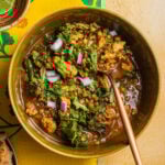 A bowl of soup with ground turkey, lentils, herbs, and red onion set atop a floral napkin.