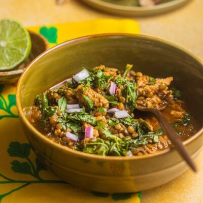 A bowl filled with turkey lentil soup with a lime in the background.