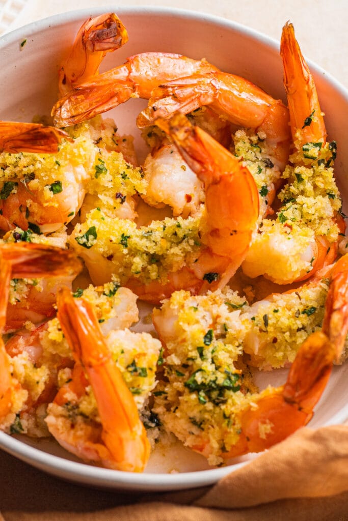 A casserole dish with shrimp tails sticking out of the pan coated in breadcrumbs.