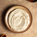 A ceramic plate with a butter bean hummus spread on a countertop.