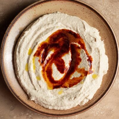 A ceramic plate dolloped with butter bean hummus and a drizzle of paprika oil.