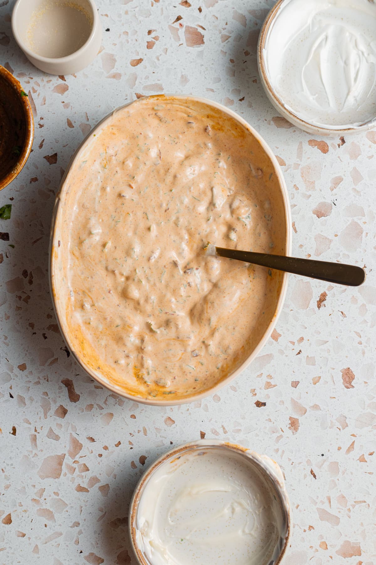 A bowl of creamy chipotle sauce on a counter top with various ingredients in the background.