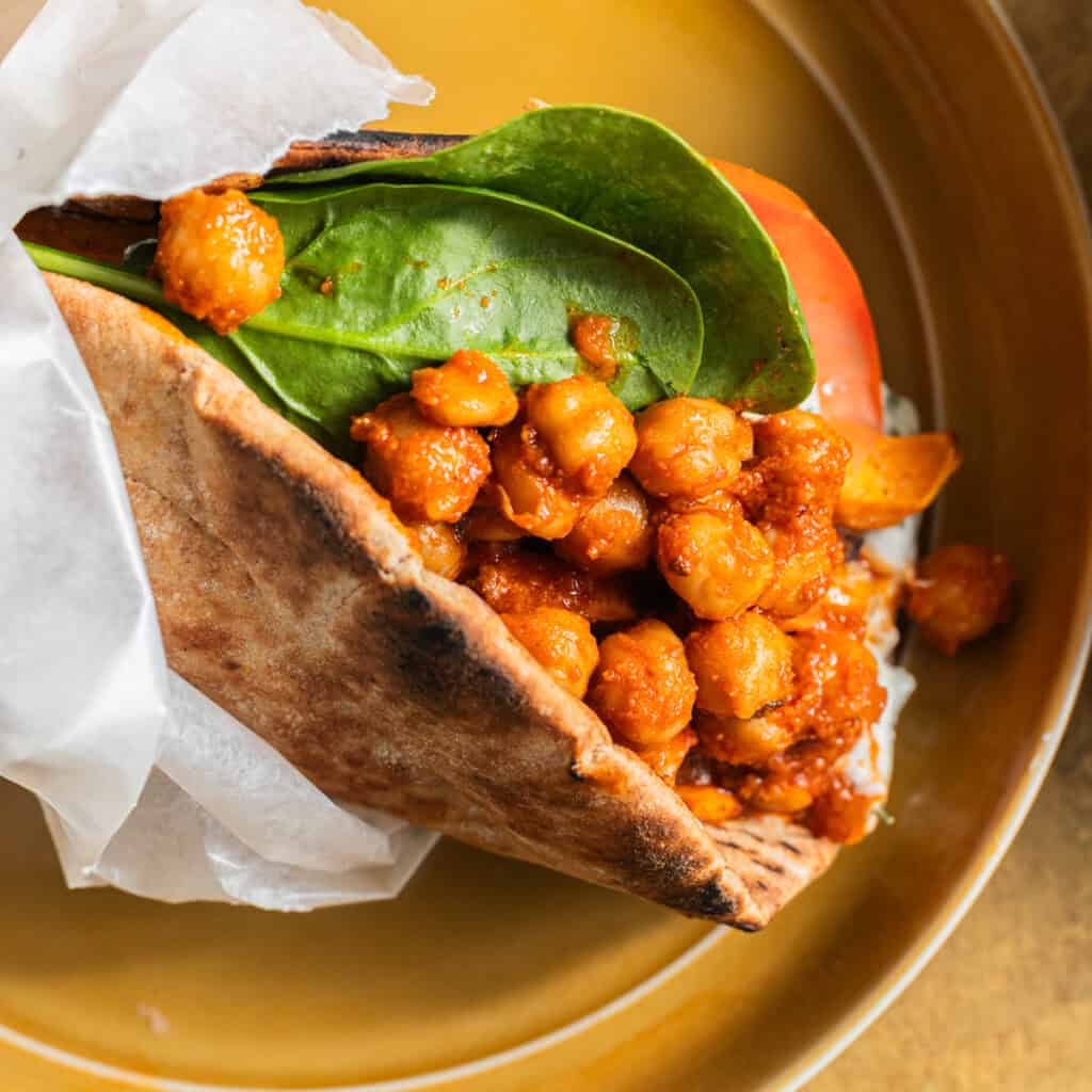 Pita wrapped up like a gyro in wax paper and stuffed with sauced chickpeas, spinach, and tomato.