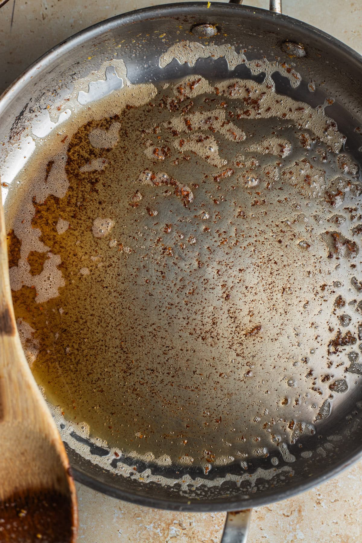 A stainless steel skillet with brown butter in it.
