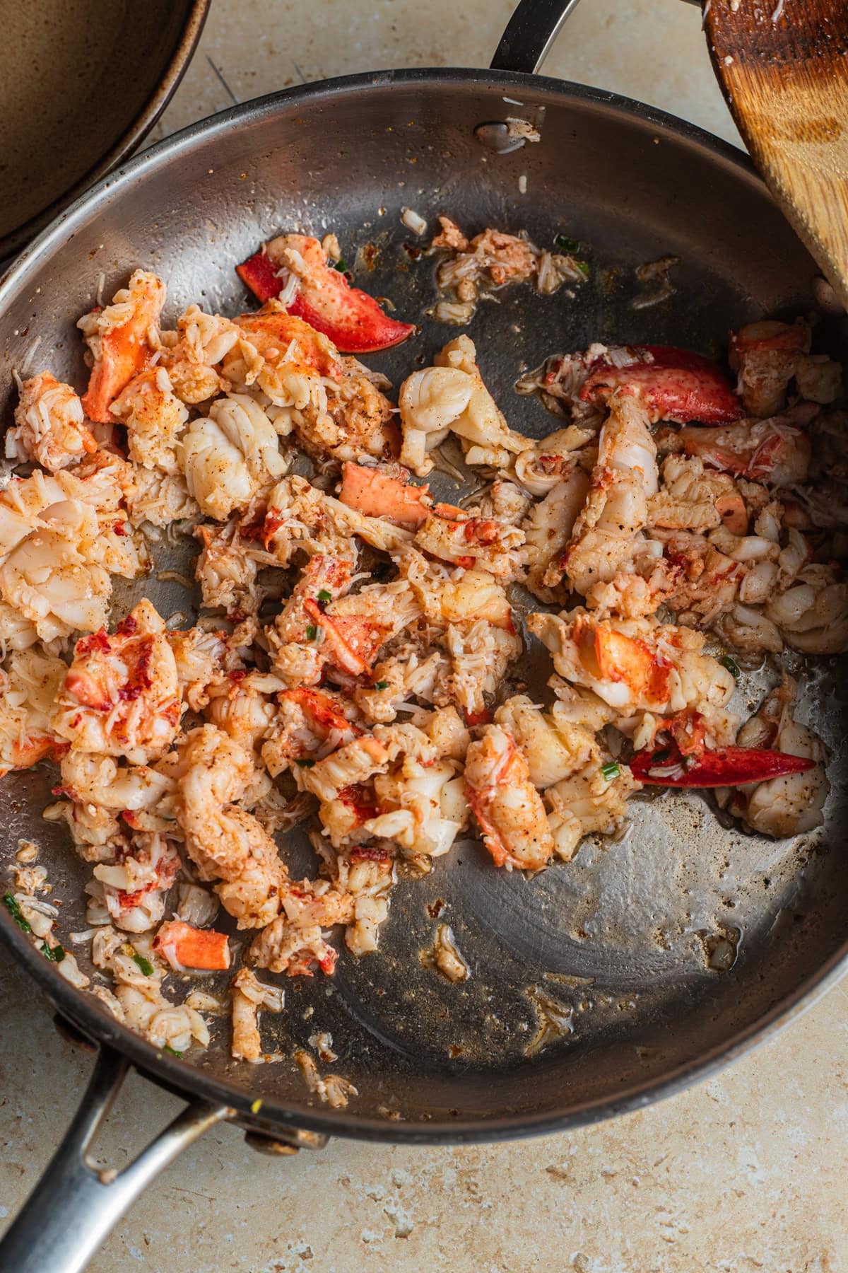 A stainless steel skillet with chopped lobster meat and chives.