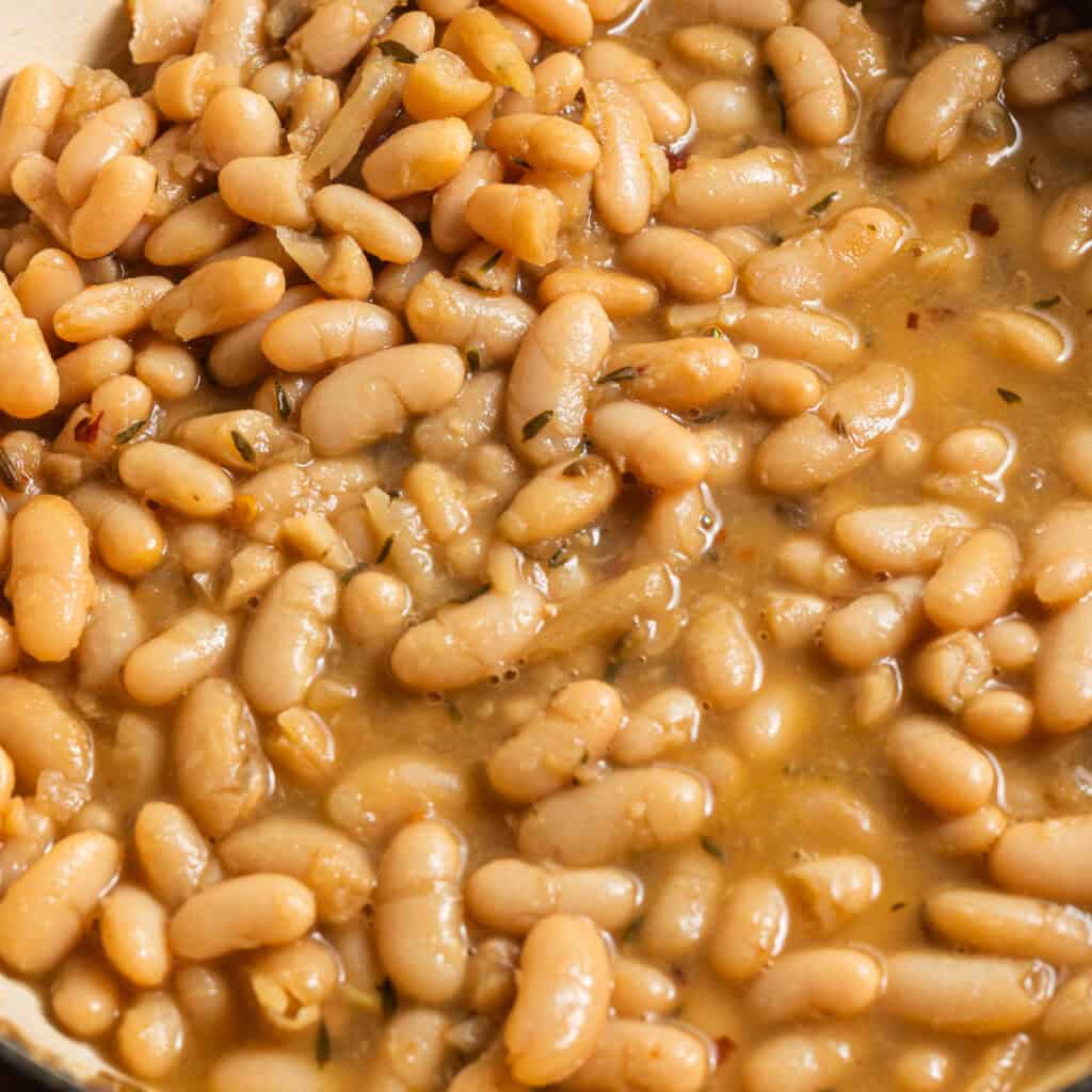 Creamy cooked white beans in a golden broth flecked with spices.