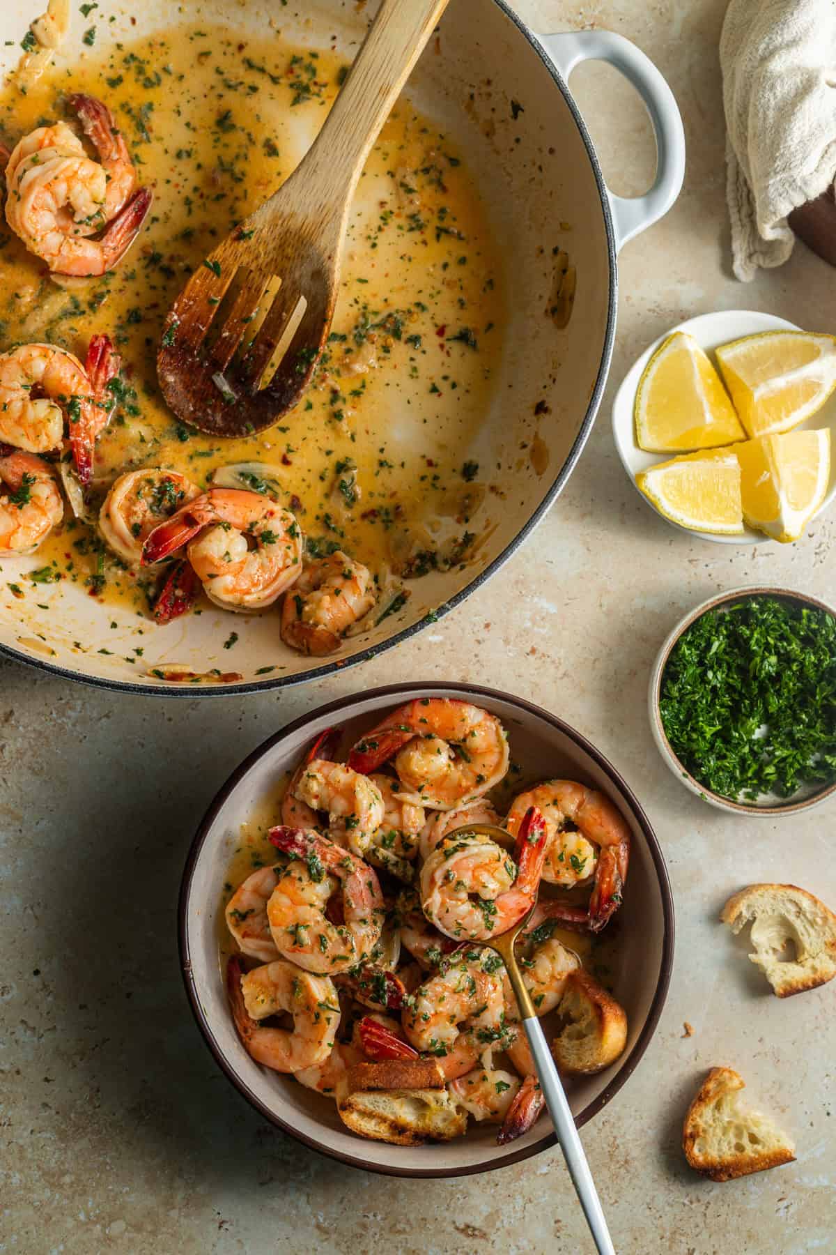 A bowl of shrimp scampi with a skillet and various ingredients in the back.