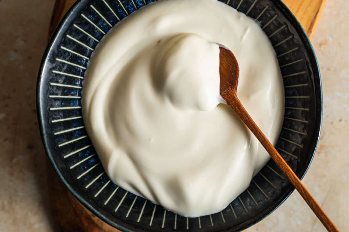 A bowl of creme fraiche with a wooden spoon in it.