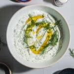 A bowl of tzatziki with a drizzle of olive oil and fresh dill.