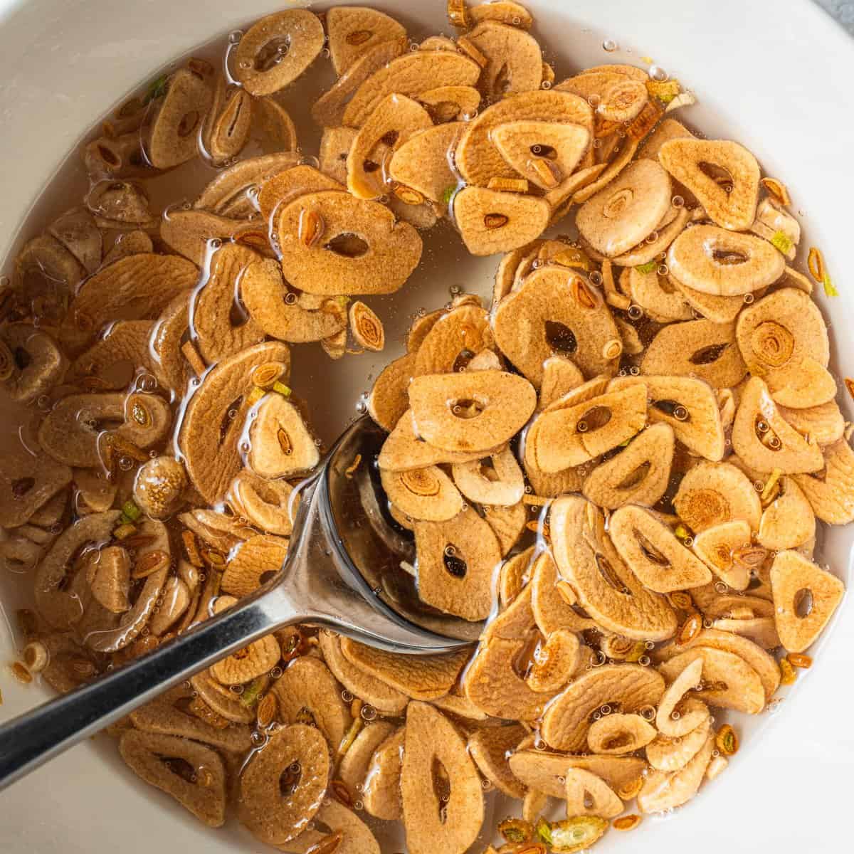A bowl of crispy garlic submerged in oil with a spoon in it.