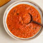 A bowl of pomodoro sauce with a wooden spoon in it.