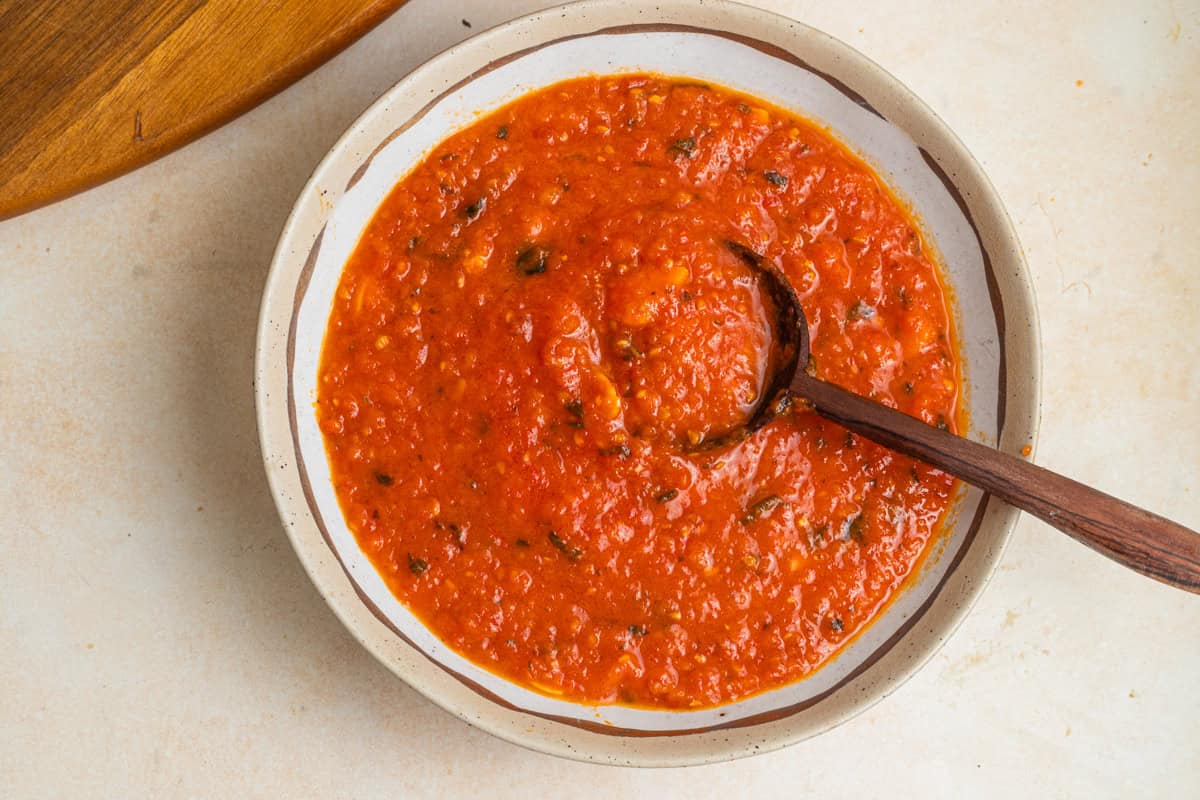 A bowl of pomodoro sauce with a wooden spoon in it.