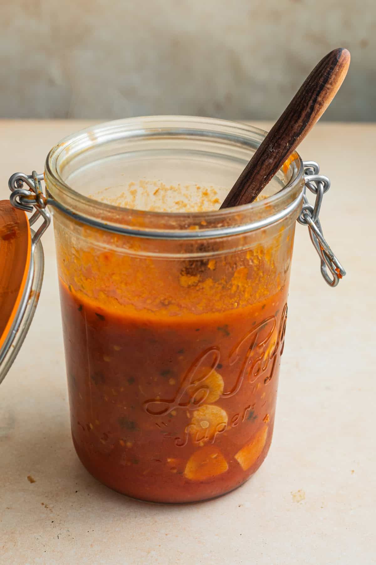 A jar of tomato sauce with a wooden spoon in it.