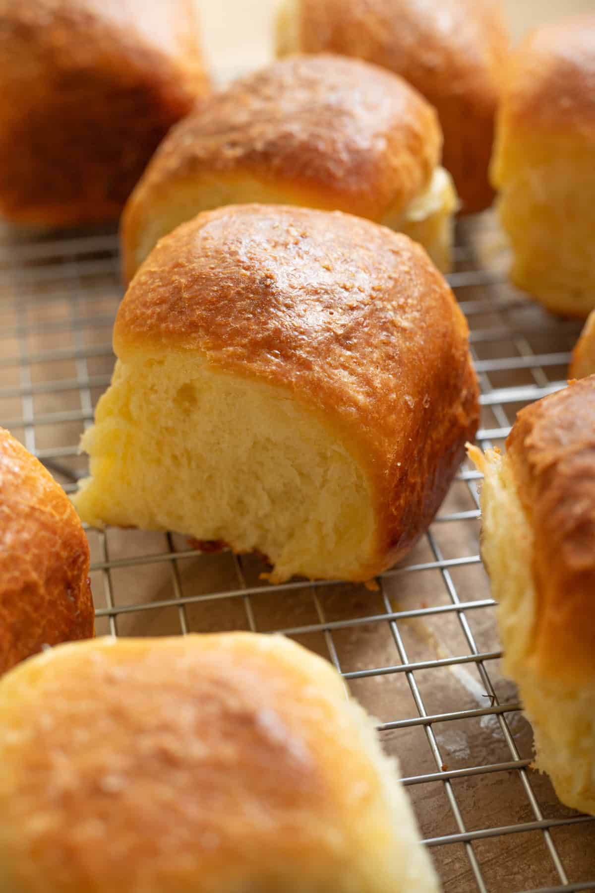 Brioche-style dinner rolls cooling on a wire rack.