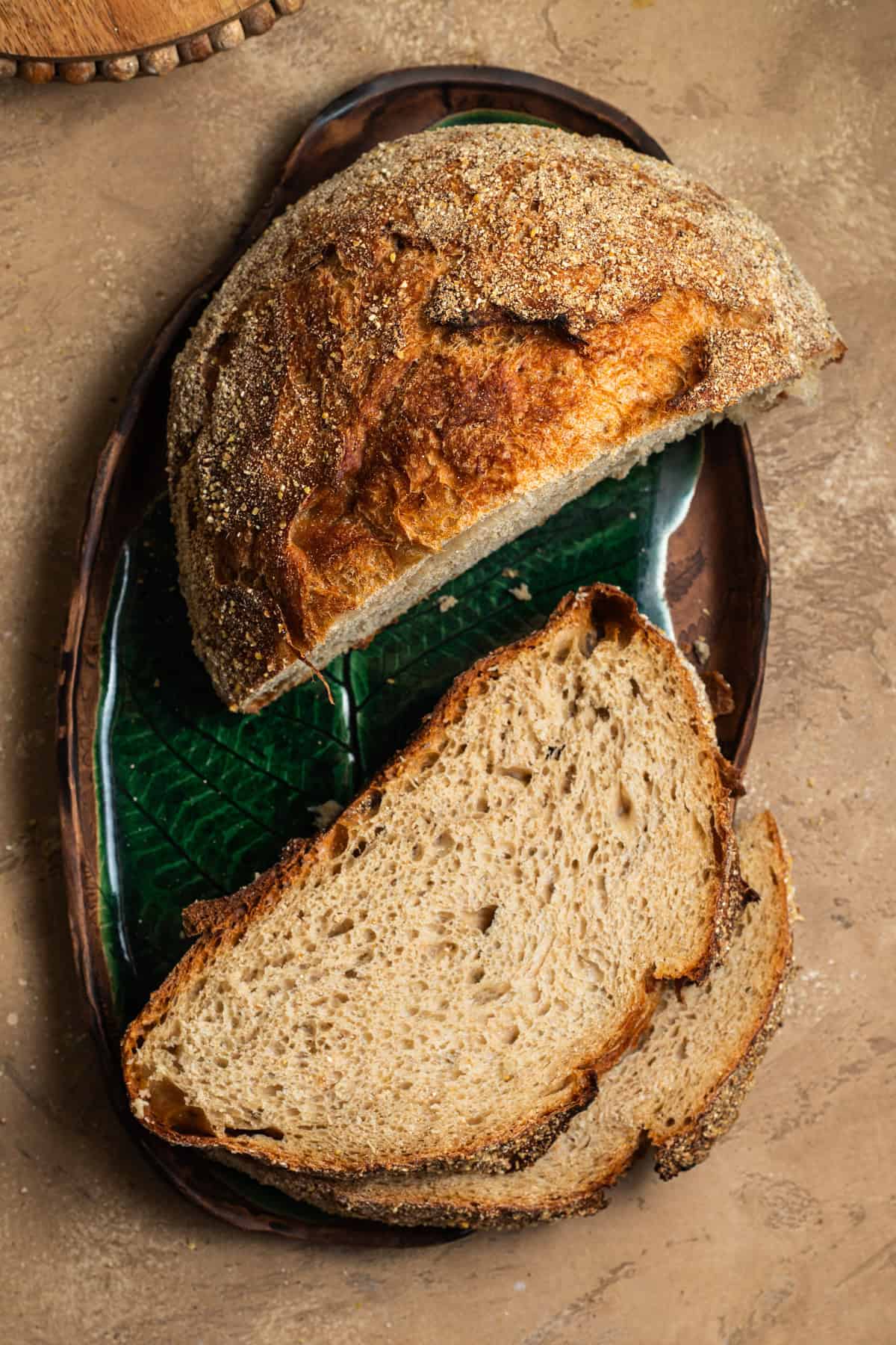 Two slices of whole-wheat bread with a half loaf of bread on an oval platter.