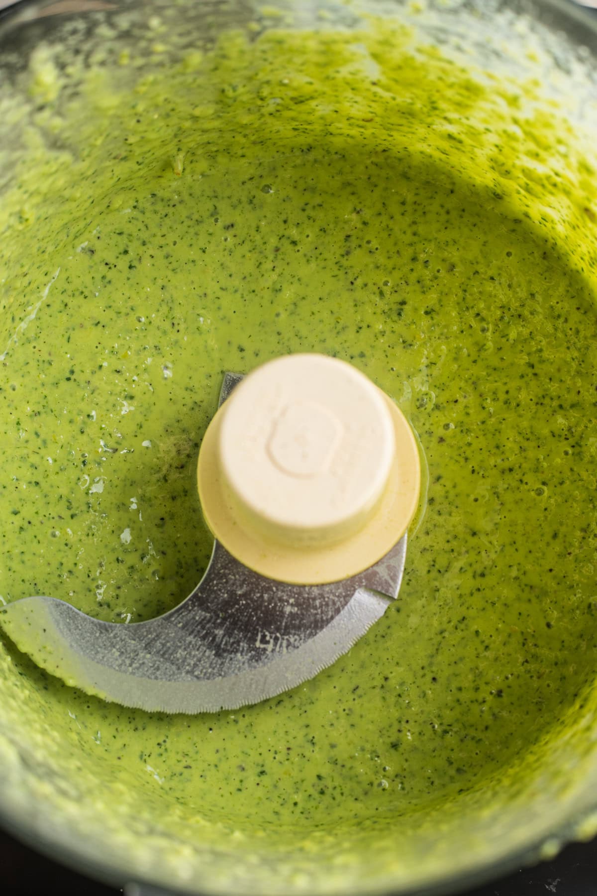 Lemon pesto sauce in a food processor with the food processor blade.