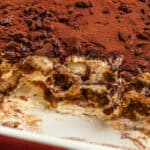 A tray of tiramisu with a scoop taken out.