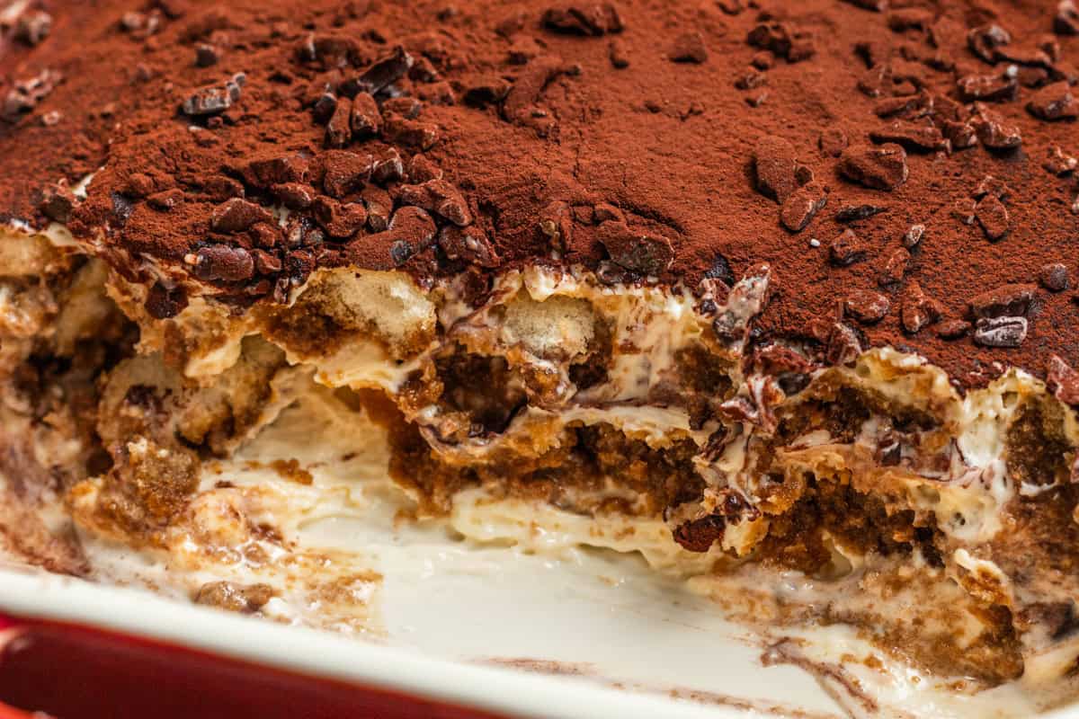 A tray of tiramisu with a scoop taken out.